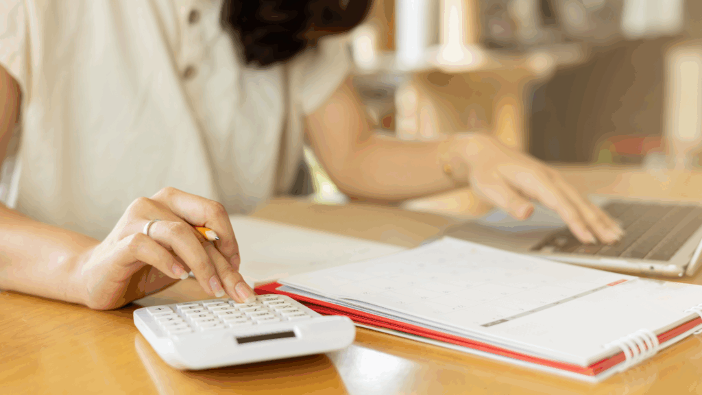Person using a calculator and sitting at a desk with a paper document.