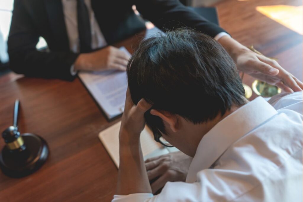 An inventor speaking to a patent lawyer, with his head in his hands