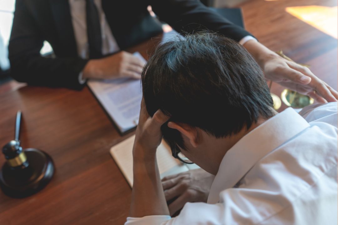 An inventor speaking to a patent lawyer, with his head in his hands