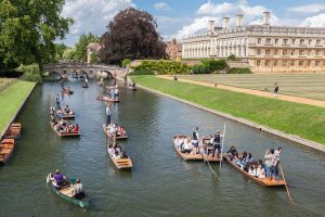 A scenic aerial shot of Cambridge, showing the river with punts on, and Cambridge university in the backdrop.