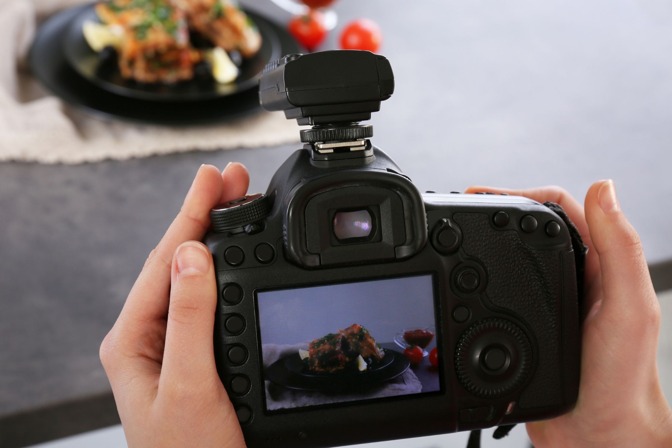 A pair of female hands holding a camera and taking a photograph