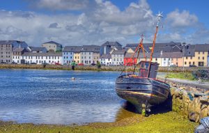 Waterfront scene in Galway, with a row of colourful houses and a boat.