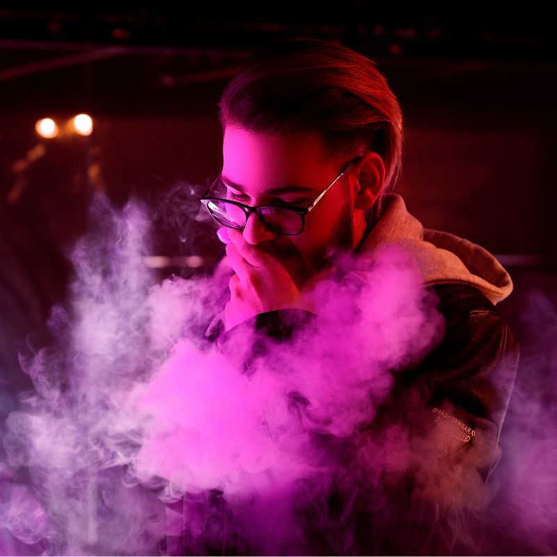A man vaping, with a cloud of smoke coming from his mouth.