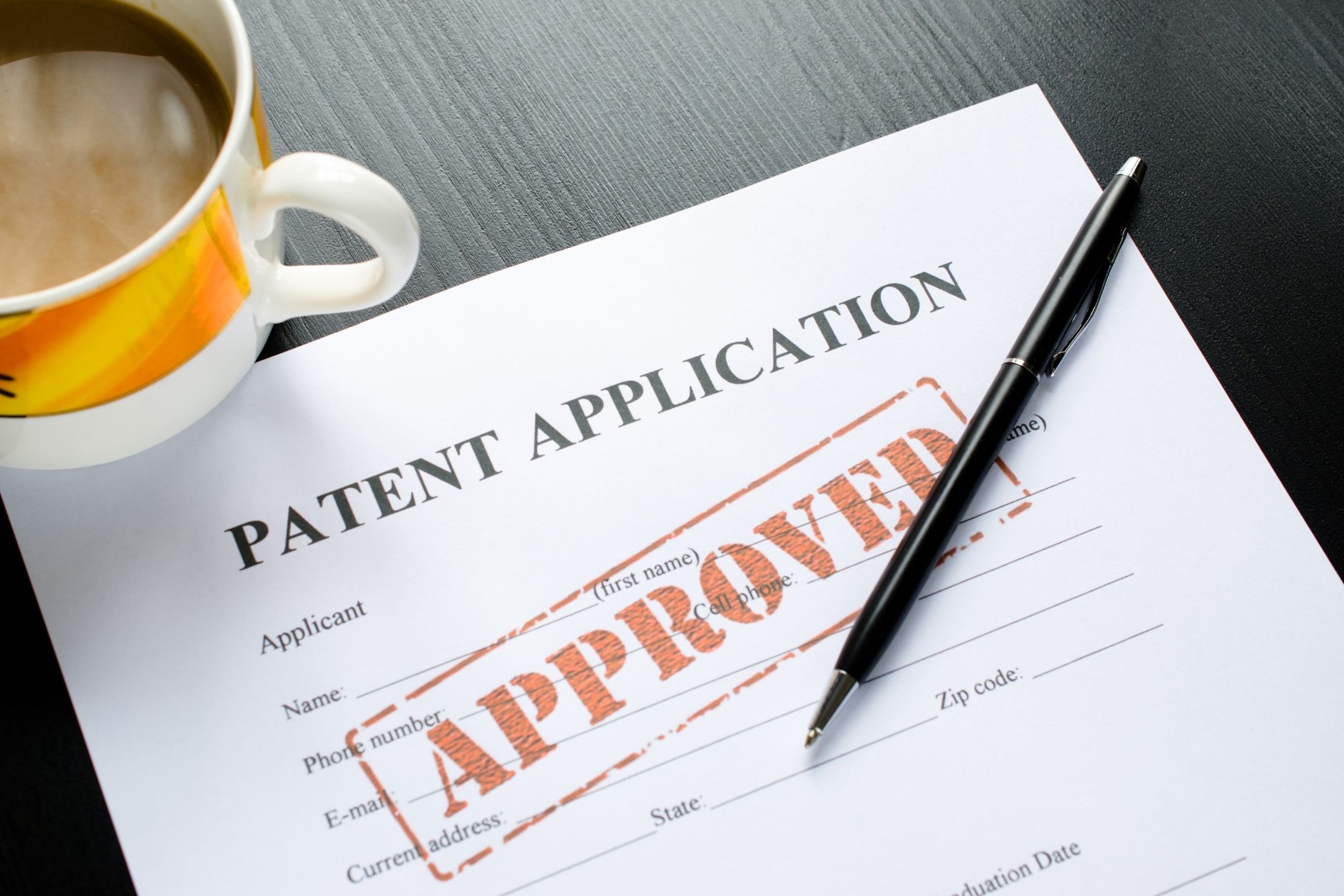 A patent application laid on a desk, with an 'approved' stamp on it.