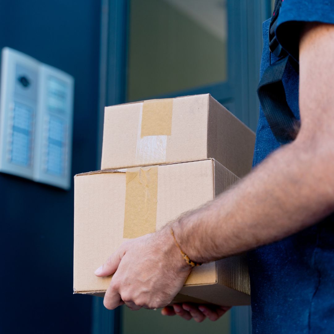 Male hands holding a stack of two delivery boxes.