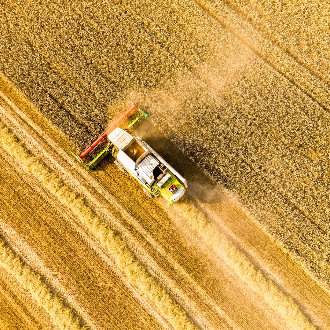 An aerial shot of a tractor ploughing through a field.
