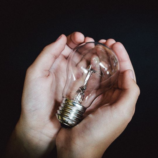 A pair of hands holding a lightbulb, representing innovation