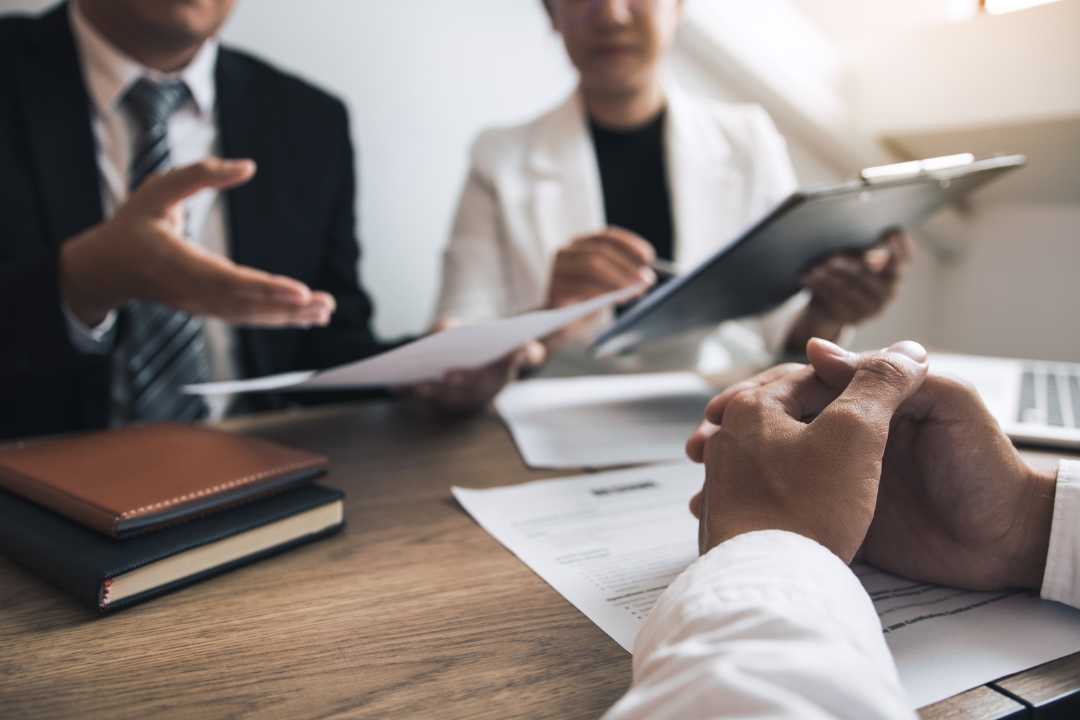 A patent lawyer and clients sat around a table, discussing a patent refusal challenge.