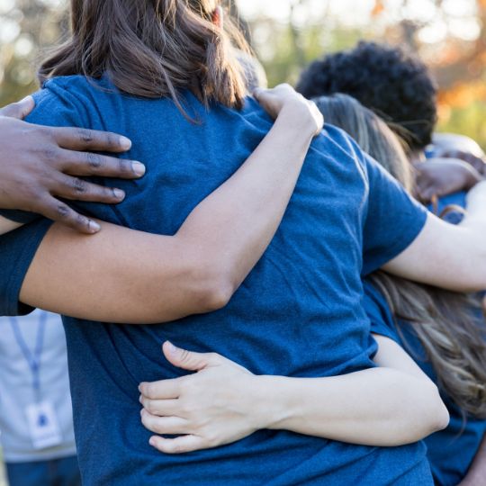 A group of charity volunteers hugging one another