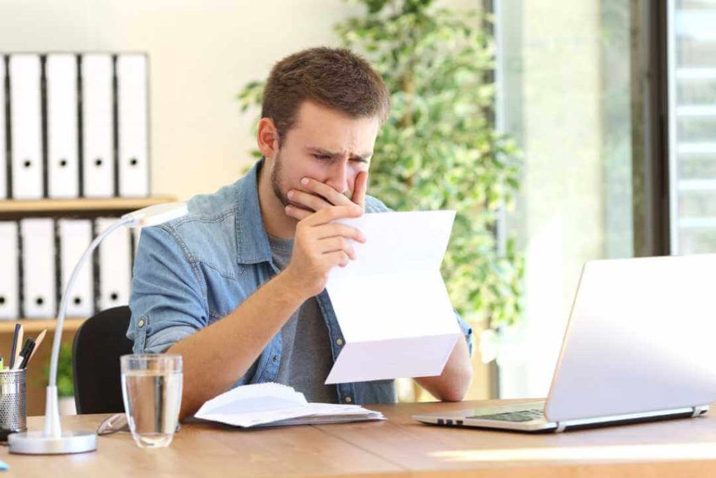 A man opening a cease and desist letter, looking very worried.