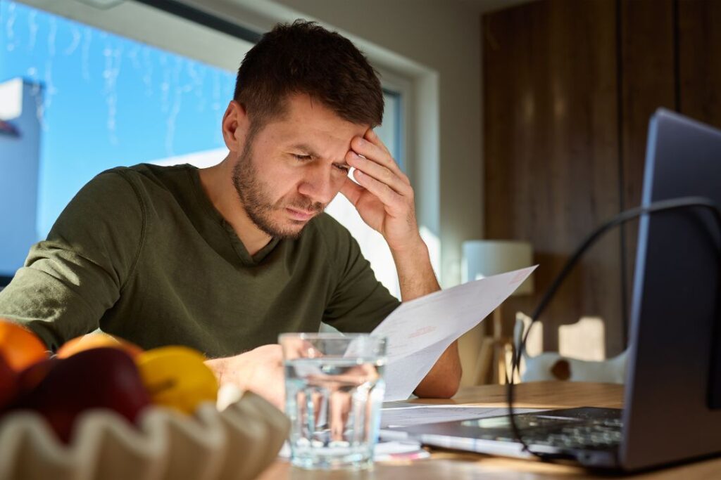 A man looking worried, opening a cease and desist letter from Dehns