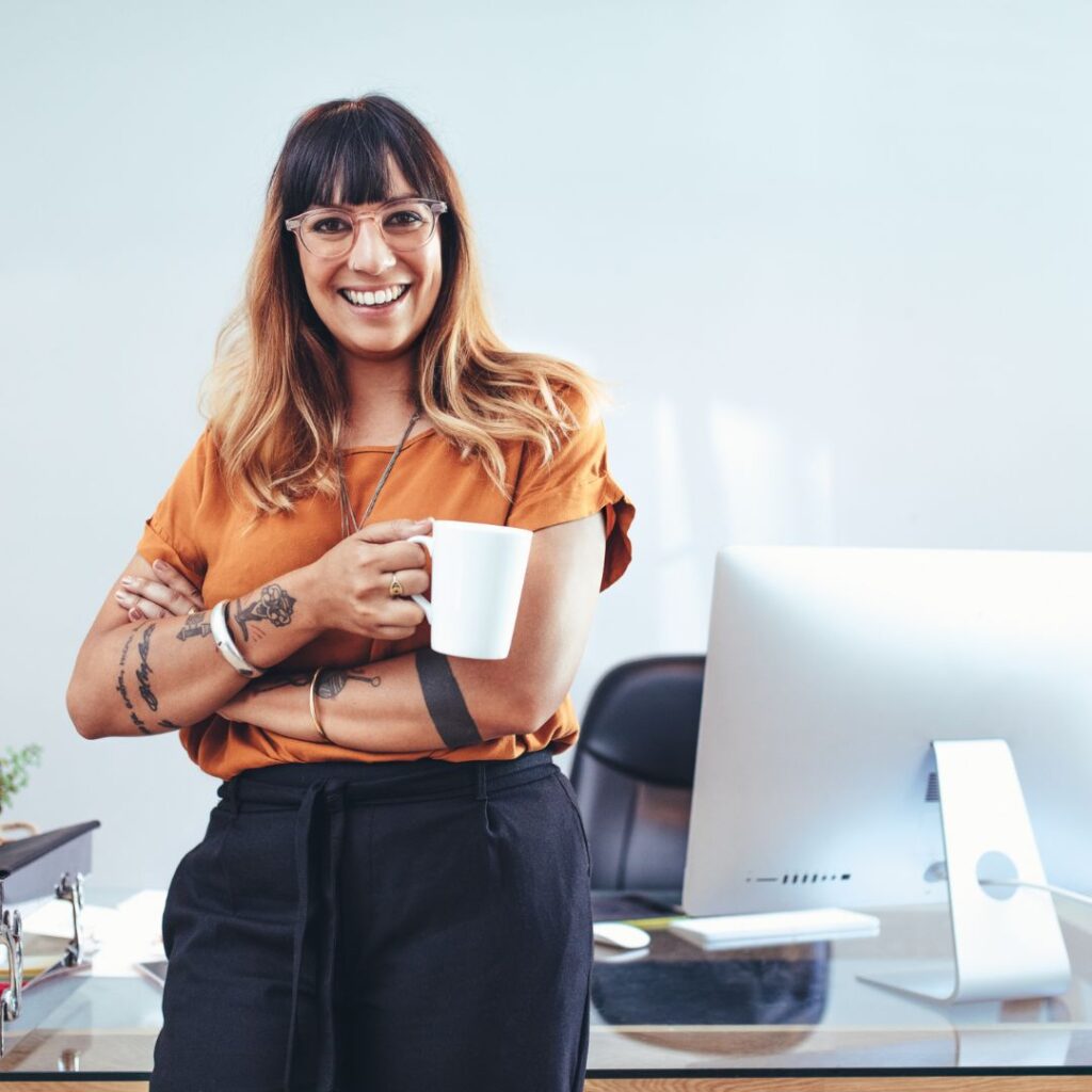 A female entrepreneur stood in her office, holding a mug